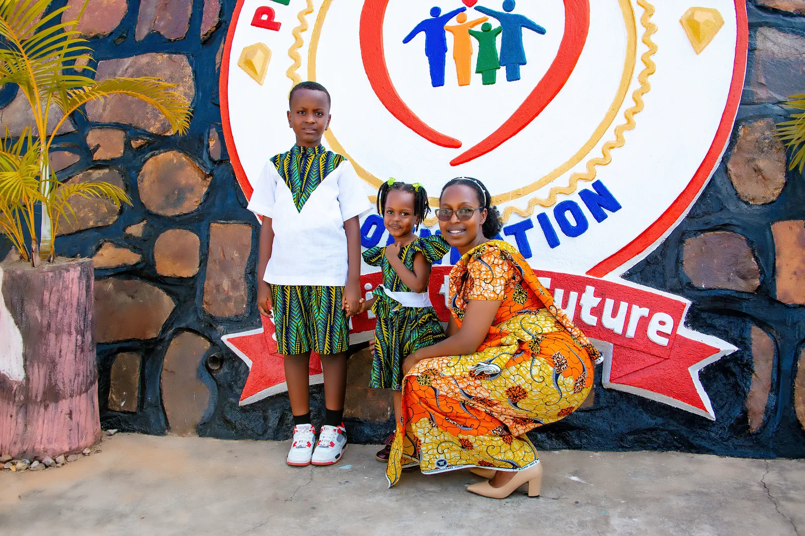 A mother with her son and daughter in front of the Precious Stones emblem