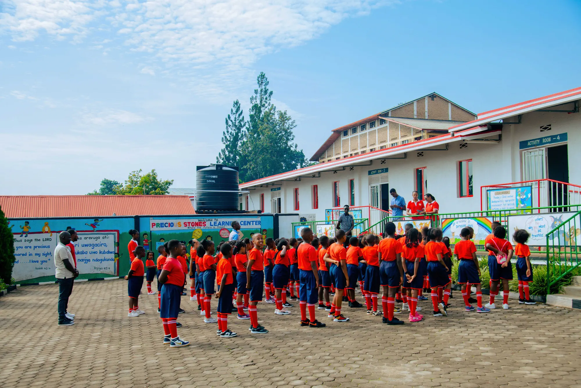 Pupils lined up for assembly in the paved yard in front of the school building