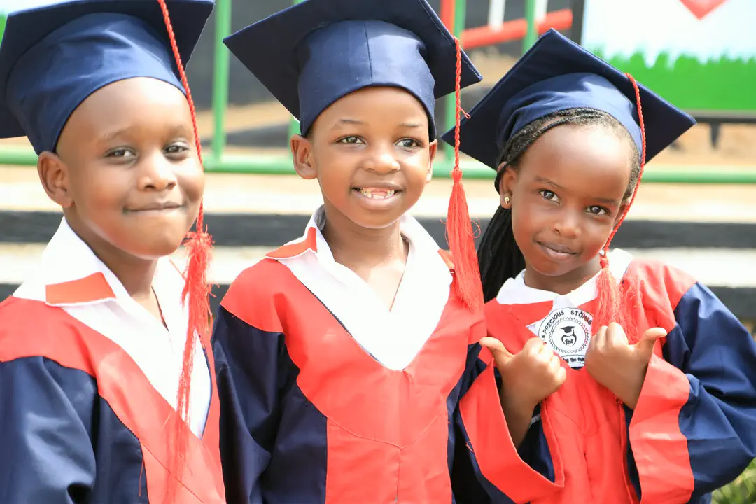Three young graduates in caps and gowns, smiling