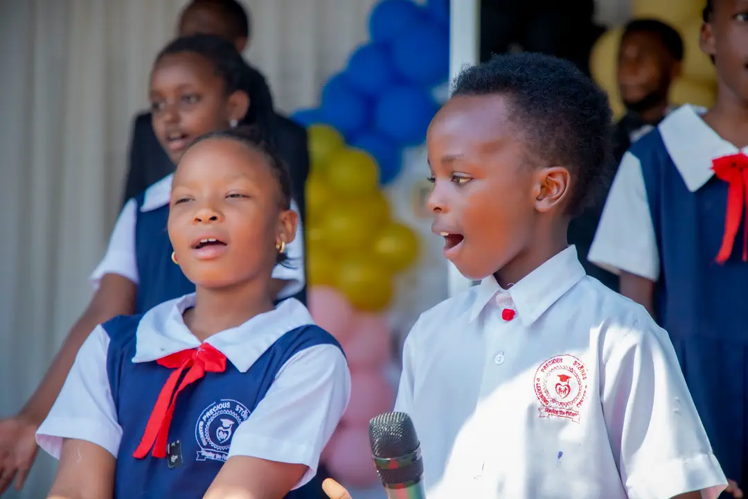 Two pupils in uniform singing on stage