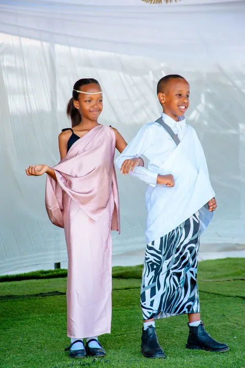 A girl and a boy on the graduation stage in traditional Rwandan dress
